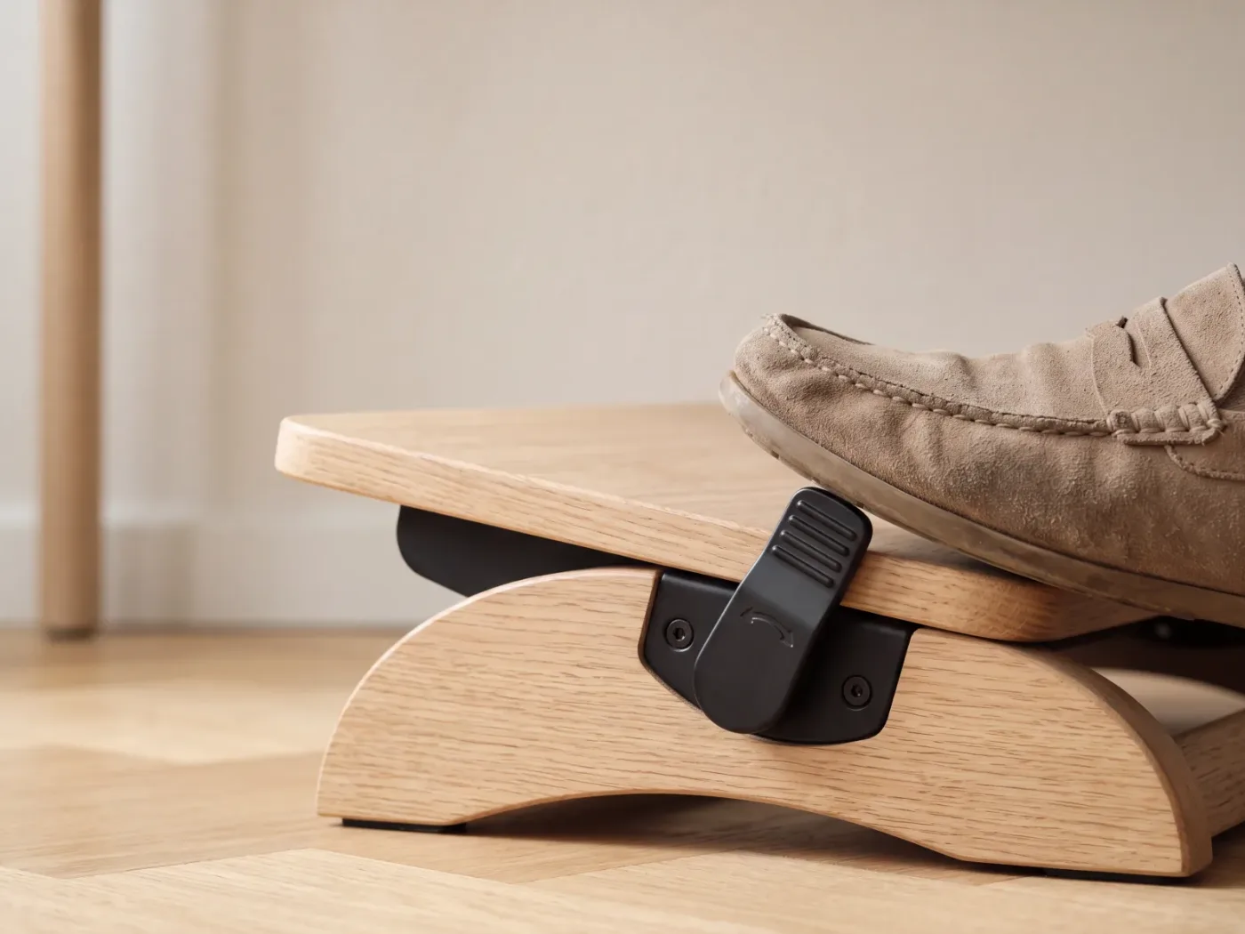 Gros plan sur le levier de réglage latéral d'un repose-pieds, actionné par la pointe d'une chaussure souple.