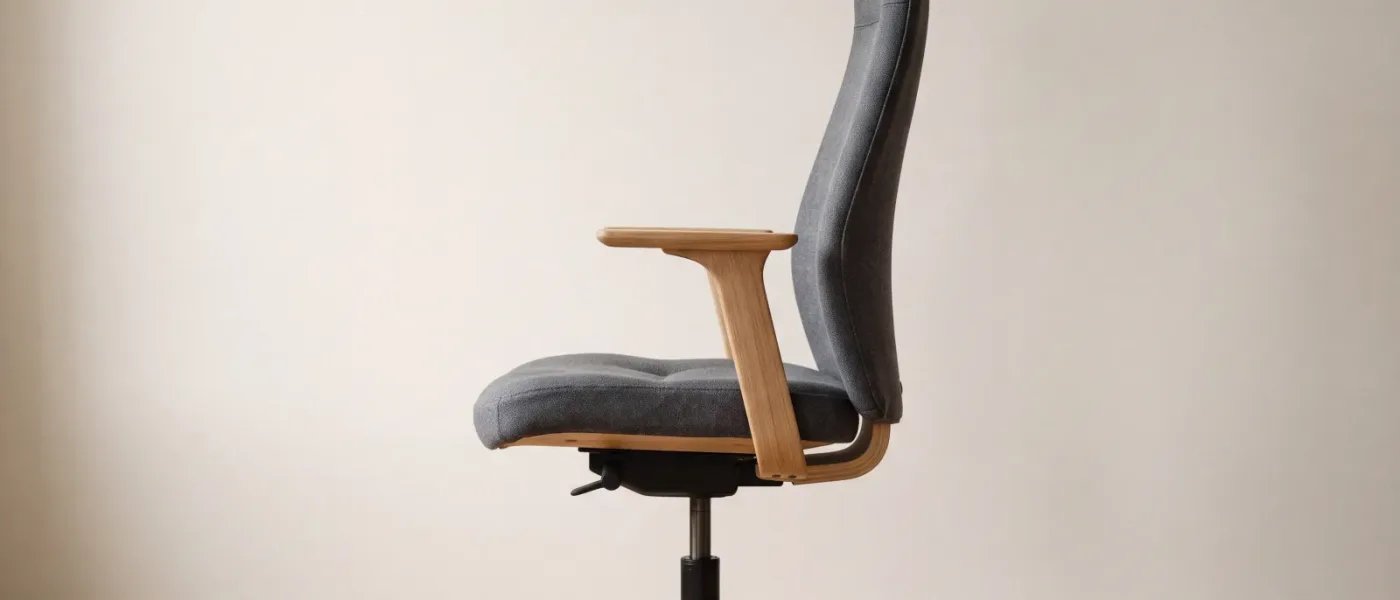 Un siège de bureau vide vu de profil, dont l'assise en tissu gris est légèrement creusée sur son tiers avant.